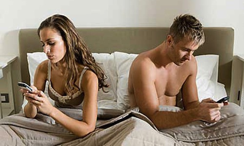 couple-au-lit-qui-regardent-leur-smarphone