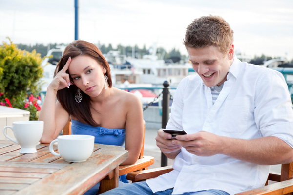 jeune-couple-homme-regarde-son-smartphone-femme-qui-fait-la-tête