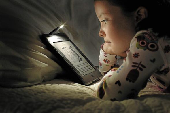 enfant-qui-lit-sur-une-liseuse-avec une lampe